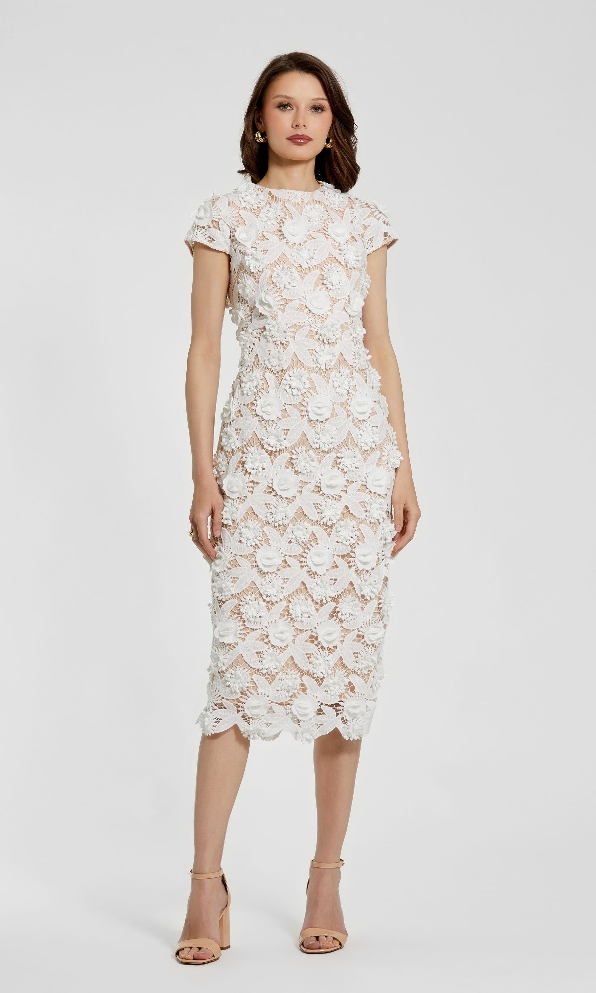 A woman stands against a plain background wearing the Mac Duggal 81022 Midi Lace Cocktail Dress in white with short sleeves, floral lace pattern, and nude heels.